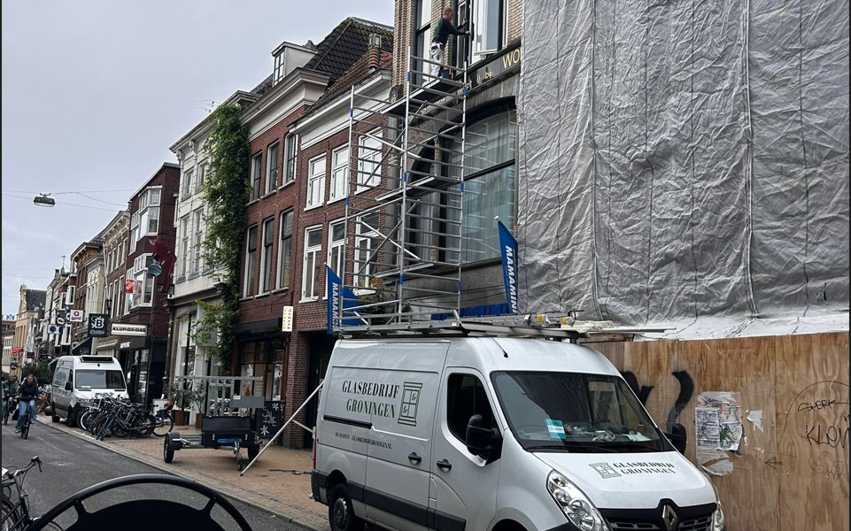 Groningse straat met steigerwerk en bedrijfsbus van Glasbedrijf Groningen