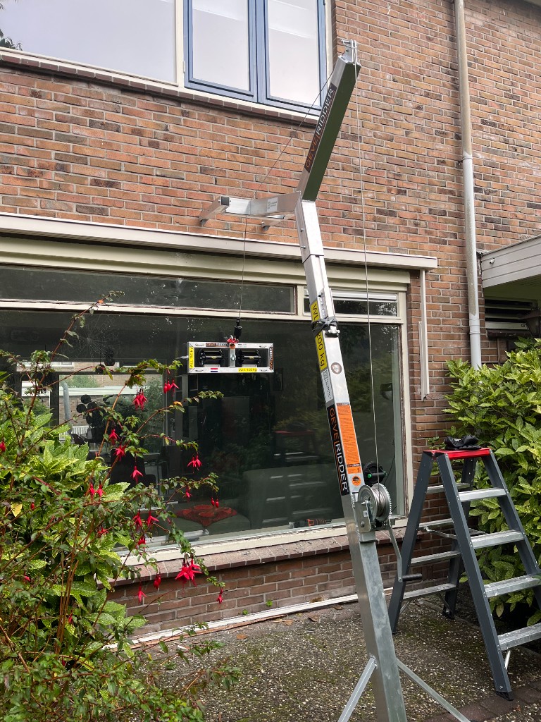 Gevelridder-kraan bij plaatsing van glas aan een rijtjeswoning